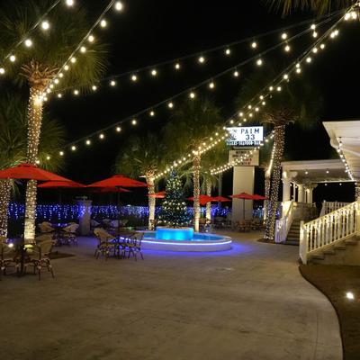 Nighttime patio with string lights and a glowing fountain.