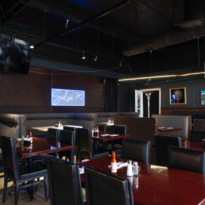 Restaurant dining area with tables, chairs and a neon wall sign.