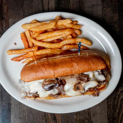Philly cheesesteak sandwich served with crispy fries.