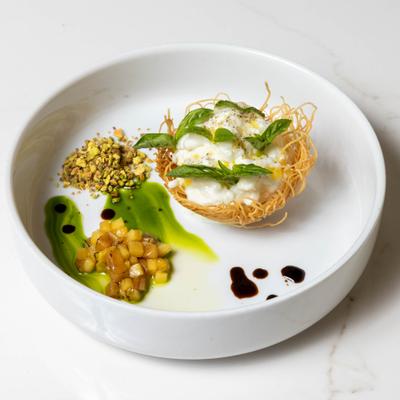 Crispy pastry filled with cream, served with basil, poached peach, and pistachios.
