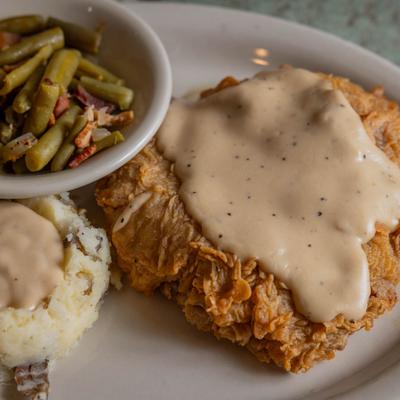 Chicken fried steak with mashed potatoes and green beans on a plate.