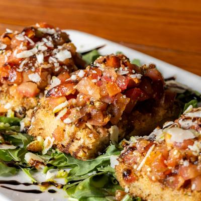 Bruschetta appetizers with tomato, basil pesto, and balsamic reduction.