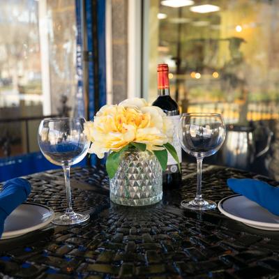 Outdoor seating area, a table with floral display, set for dining.