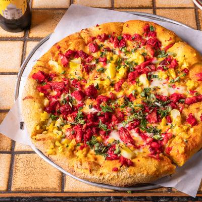 Tandoori Chicken Pizza served on a metal plate.