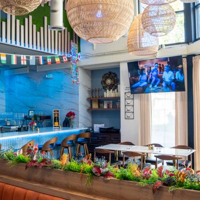 Interior featuring wicker light fixtures hanging from the ceiling and a vibrant blue bar area.