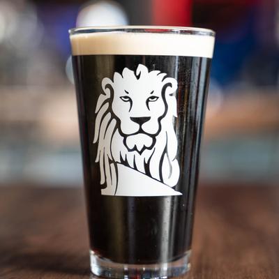 Dark beer in a glass with a white lion logo