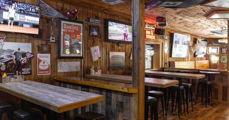 Rustic sports bar interior with wooden walls, multiple TV screens