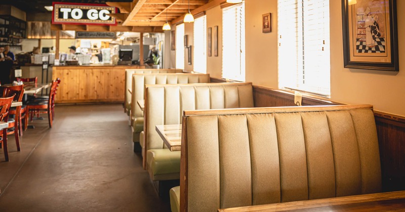 Interior, dining area, padded seating booths with wooden top tables, windows with blinds