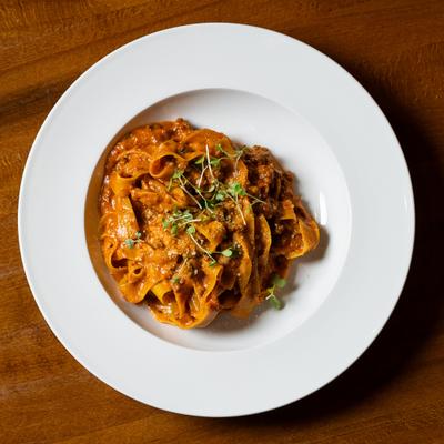 Pappardelle Bolognese garnished with microgreens.
