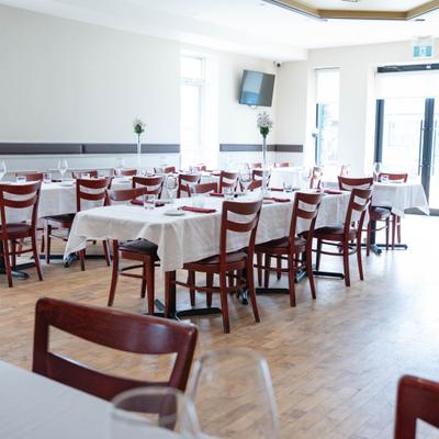 Bright restaurant dining room featuring white tablecloth tables and large windows.