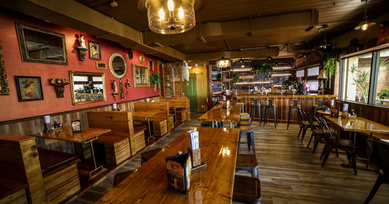 Interior, wooden tables, chairs and benches, framed pictures on the wall, bar in the back