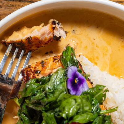 Grilled salmon with rice and greens in a creamy garlic wine sauce.