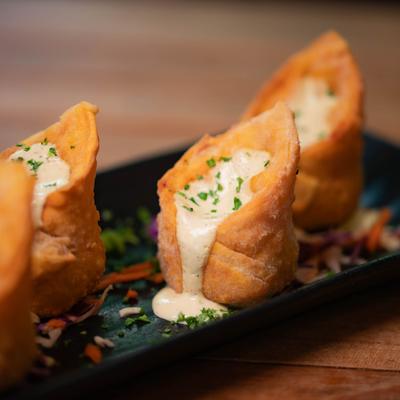 Chicken fajita Wontons topped with creamy sauce and chopped chives.