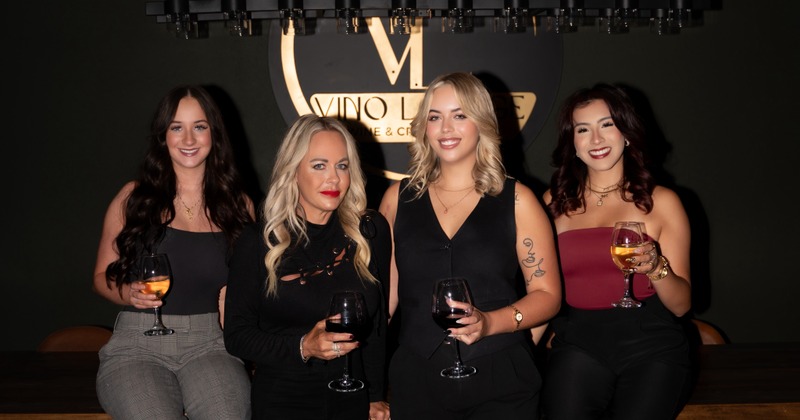 Vino Lounge Team members pose in front of a "Vino Lounge" sign