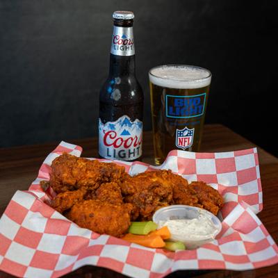 Mild buffalo wings served on the table with bottle and glass of beer.