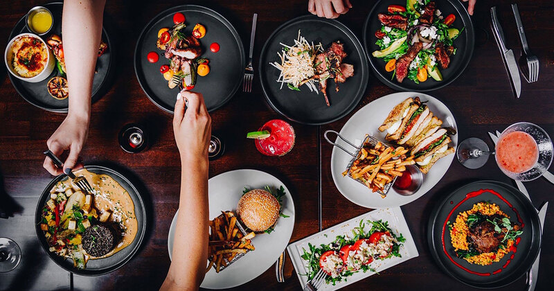 Top view of a table with assorted dishes, guests helping themselves to food