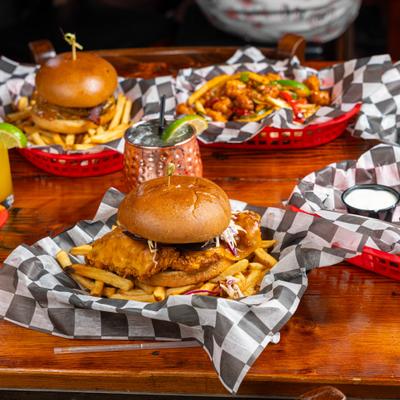 Fried chicken sandwich and burgers served with fries in red plastic baskets.
