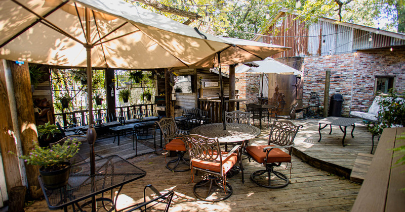 Patio with tables and chairs ready for guests and white parasols