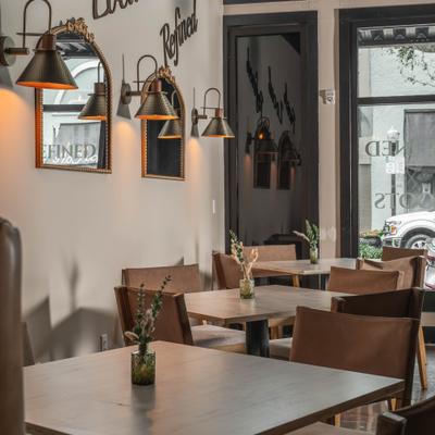 Dining space with wall lamps, mirrors and wooden tables.