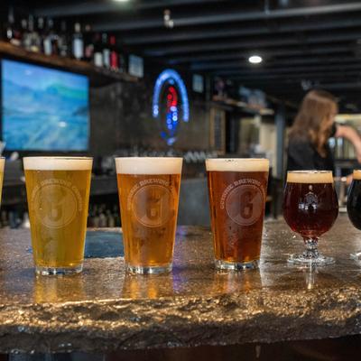 Six glasses of various beers on a bar top.