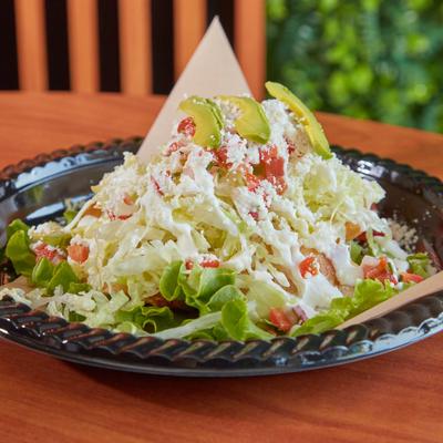 Taco salad with lettuce, cheese, tomatoes, and avocado.