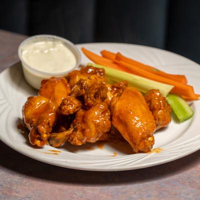Buffalo wings served with dipping sauce and vegetable sticks.