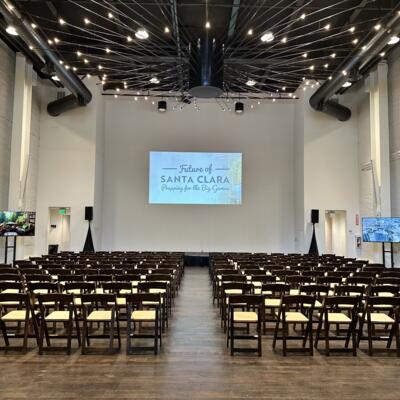 The room with high ceilings, exposed ducts, and radiating string lights..