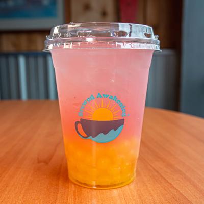Dragon fruit lemonade in plastic cup with Brewed Awakening sign.