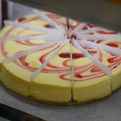 Raspberry swirl cheesecake placed in a display case.