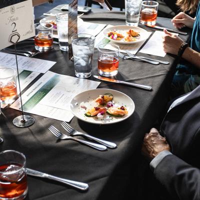 Guests seated around a table with appetizers, cocktails, and menus.
