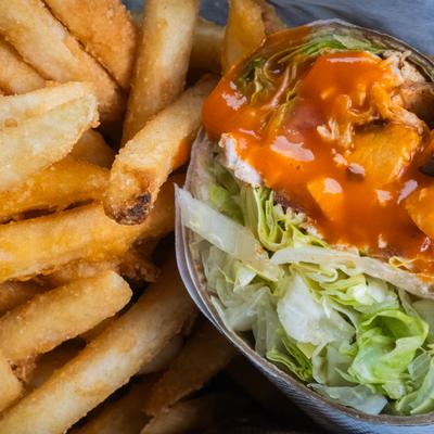 Buffalo chicken wrap with lettuce, buffalo sauce, and a side of fries.