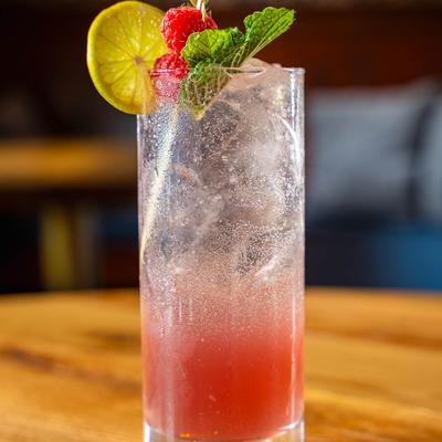 Raspberry Mojito glass, garnished with lemon, mint and raspberries.