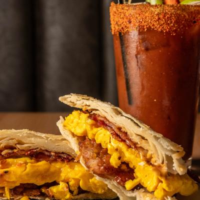 Breakfast sandwich sliced in half and served with a cocktail.