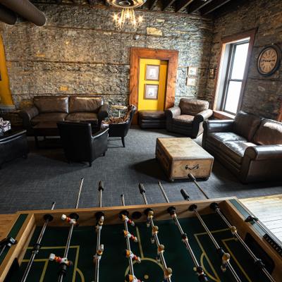 Industrial lounge with stone walls, leather seating, and foosball.