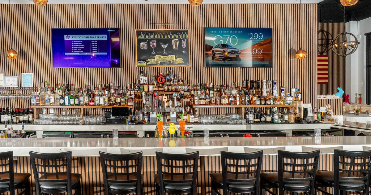 Modern bar interior - black chairs, white counter, sleek decor, liquor bottles, wall-mounted screens