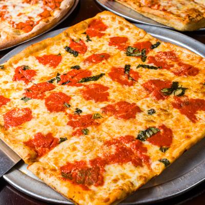 Grandma pizza with tomato sauce dollops and basil.