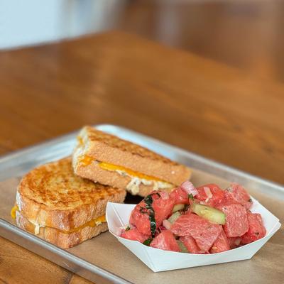 Grilled cheese sandwich served with a watermelon salad.