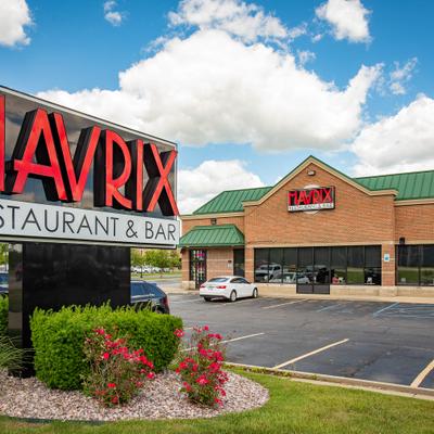 Restaurant outdoor signage with a parking lot and a storefront in the background.