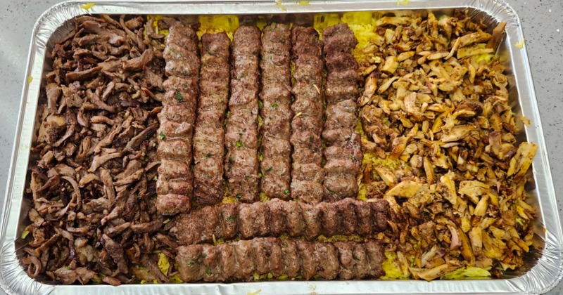 Three types of meat over yellow rice on a tray