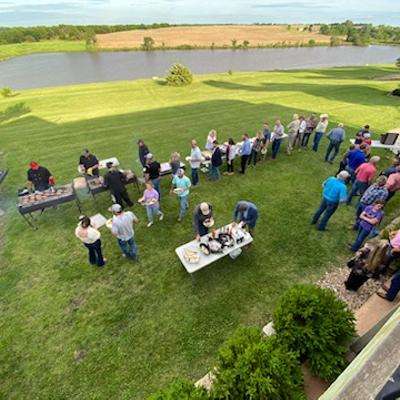 Outdoor BBQ party, people on a lawn viewed from the terrace.
