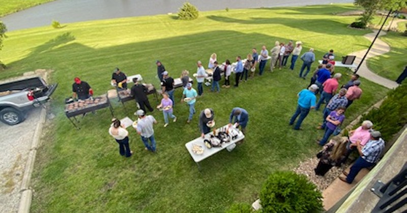 A view from a terrace of people beneath attending a BBQ party on the lawn