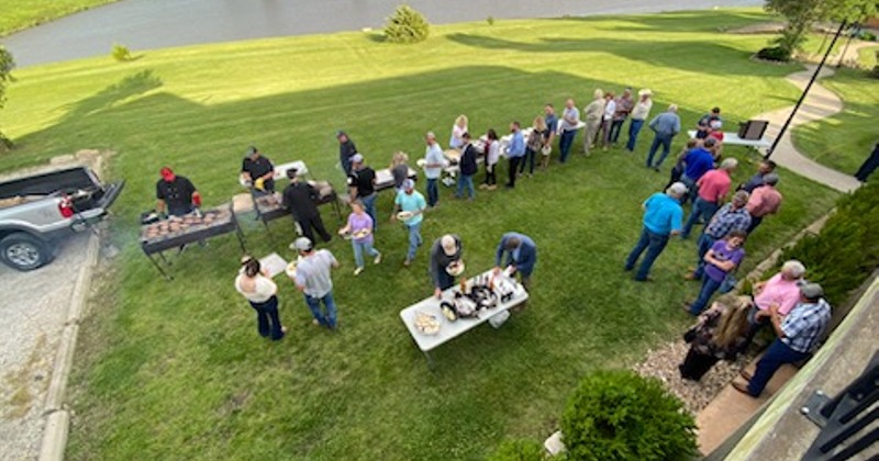 A view from a terrace of people beneath attending a BBQ party on the lawn