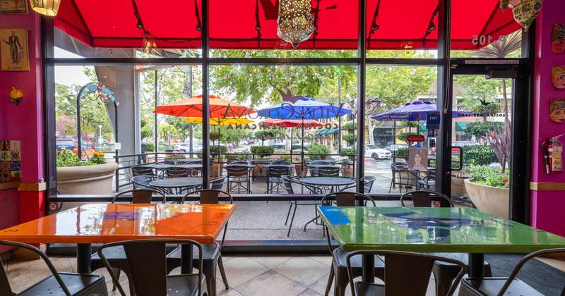 Interior of a colorful restaurant with vibrant tables and a view of outdoor seating