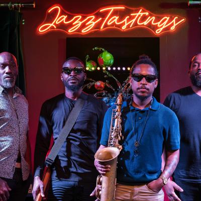 Music band posing on the stage with neon sign in the background.