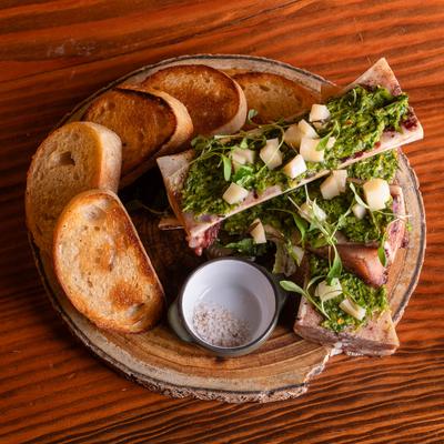 A plate of roasted bone marrow with pickled cassava, jerk chimichurri, and crostini.