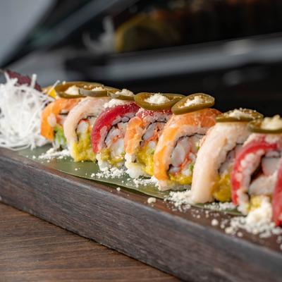 Colorful sushi rolls topped with jalapenos and cheese.