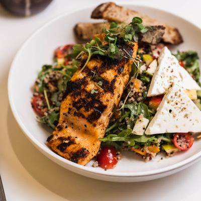 Grilled salmon over arugula salad with cherry tomatoes, quinoa, and feta cheese.