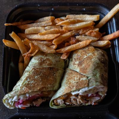 Chicken wrap halves served with crispy fries in a takeout container.