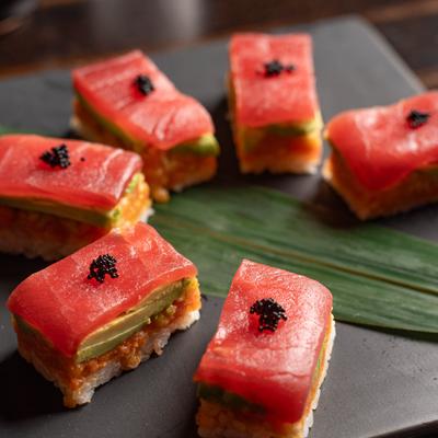 Tuna Crispy Rice garnished with black tobiko, served over a bamboo leaf.