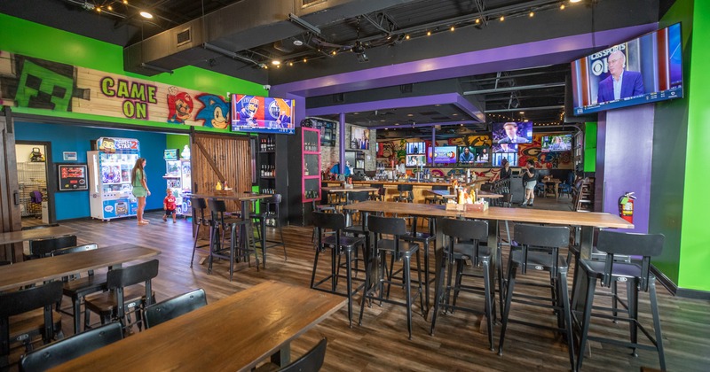 Interior, wide view to diner and bar area, tables and chairs, screens, game consoles